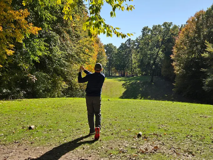 Golfer mid-swing on a wooded fairway